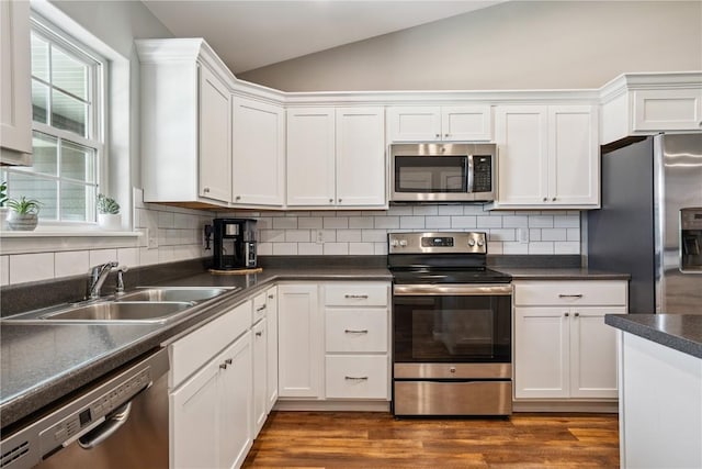 3016 Sherwood Dr, Marion, IA 52302 - kitchen featuring appliances with stainless steel finishes, lofted ceiling, white cabinets, dark countertops, and backsplash