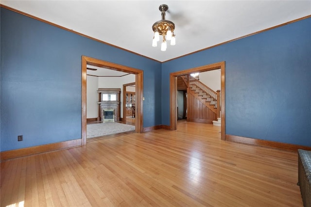 103 10th Ave SW, Mount Vernon, IA 52314 - unfurnished room featuring a chandelier, light wood-type flooring, stairs, ornamental molding, and a glass covered fireplace
