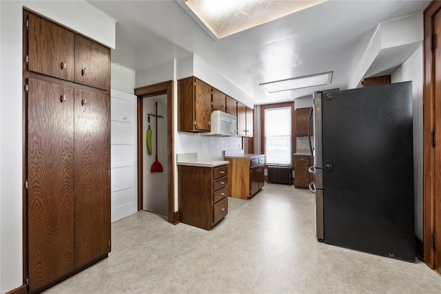 103 10th Ave SW, Mount Vernon, IA 52314 - kitchen featuring freestanding refrigerator, white microwave, radiator, light flooring, and light countertops