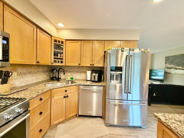 104 Oberlin St, Iowa City, IA 52245 - kitchen featuring appliances with stainless steel finishes, light stone countertops, backsplash, light wood-style floors, and glass insert cabinets