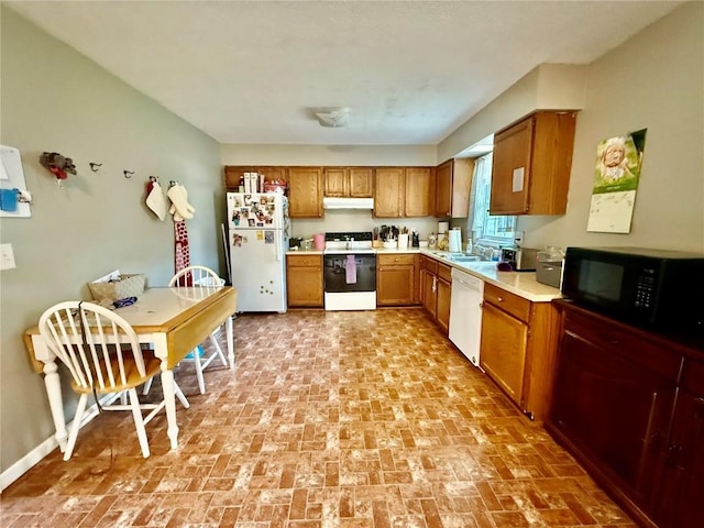 507 Maplewood Dr, Center Point, IA 52213 - kitchen with white appliances, under cabinet range hood, brown cabinets, and brick patterned floors