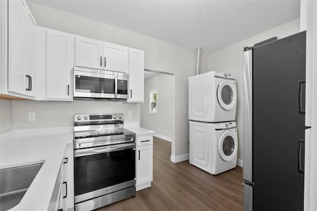 1356 Hinkley Ave NW, Cedar Rapids, IA 52405 - kitchen featuring stainless steel appliances, stacked washer / drying machine, dark wood-type flooring, white cabinetry, and light countertops