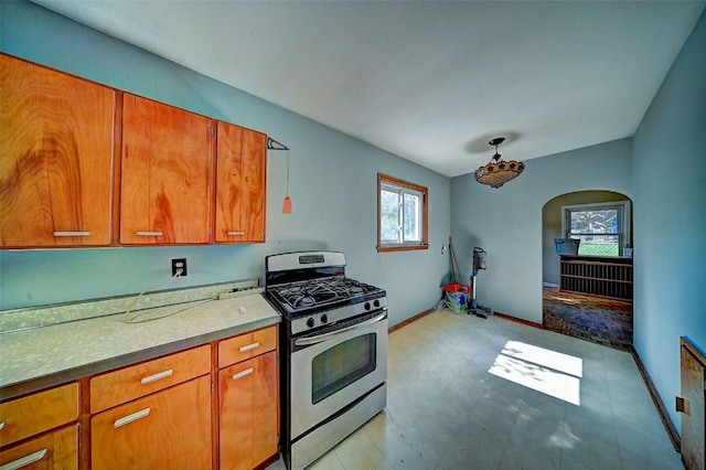 1640 11th St NW, Cedar Rapids, IA 52405 - kitchen featuring stainless steel gas range oven, brown cabinetry, arched walkways, and light flooring