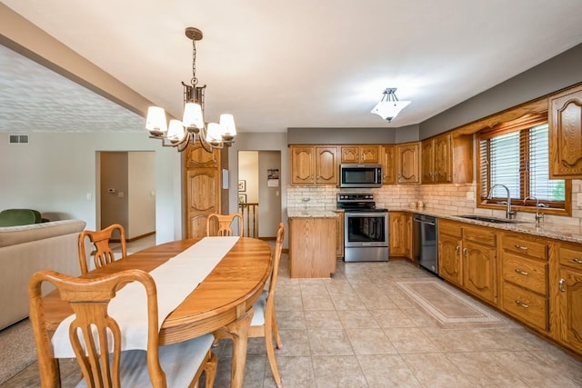 1595 17th Ave, Marion, IA 52302 - kitchen featuring stainless steel appliances, decorative backsplash, a chandelier, brown cabinets, and light tile patterned flooring
