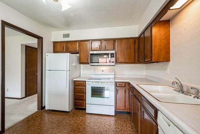 809 Kerry Ln SE Unit 66, Cedar Rapids, IA 52403 - kitchen featuring white appliances, light countertops, a textured ceiling, and brown cabinetry