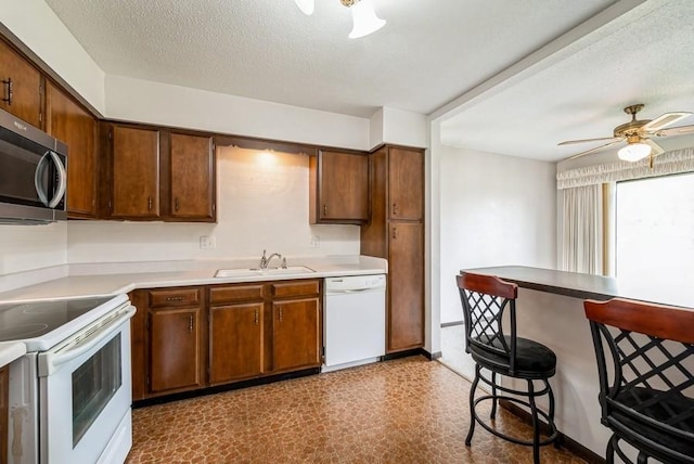 809 Kerry Ln SE Unit 66, Cedar Rapids, IA 52403 - kitchen with white appliances, a kitchen bar, tile patterned floors, a ceiling fan, and light countertops