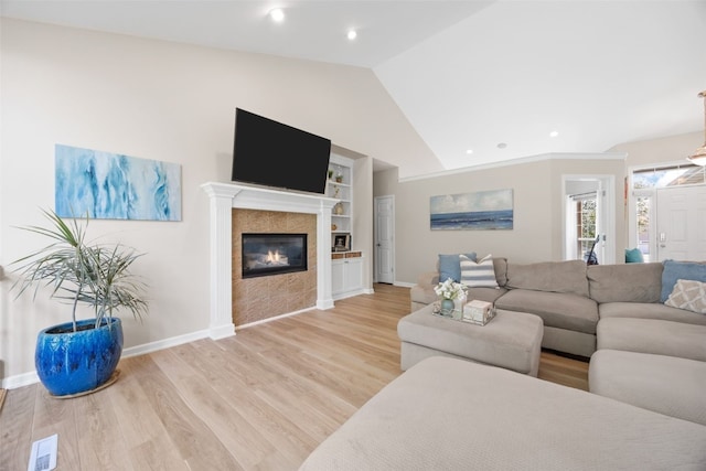 422 Rock Ridge Rd NW, Cedar Rapids, IA 52405 - living room featuring vaulted ceiling, built in shelves, light wood-style flooring, a tiled fireplace, and recessed lighting