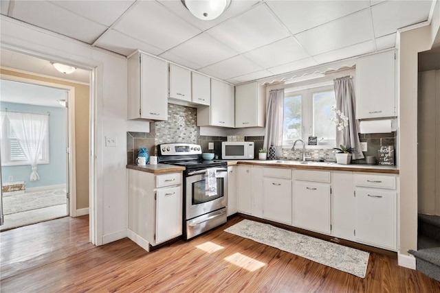 100 W Short St, Solon, IA 52333 - kitchen featuring electric stove, white microwave, white cabinets, light wood-type flooring, and a paneled ceiling
