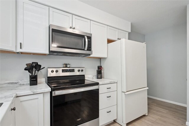 75 Jefferson Ave SW, Swisher, IA 52238 - kitchen with appliances with stainless steel finishes, light wood-type flooring, white cabinetry, and light stone counters