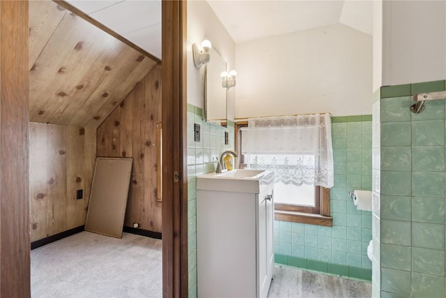 1727 Grande Ave SE, Cedar Rapids, IA 52403 - bathroom with lofted ceiling, vanity, tile walls, and wainscoting