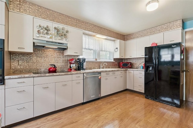 1727 Grande Ave SE, Cedar Rapids, IA 52403 - kitchen featuring black appliances, light wood-style floors, light countertops, under cabinet range hood, and white cabinetry