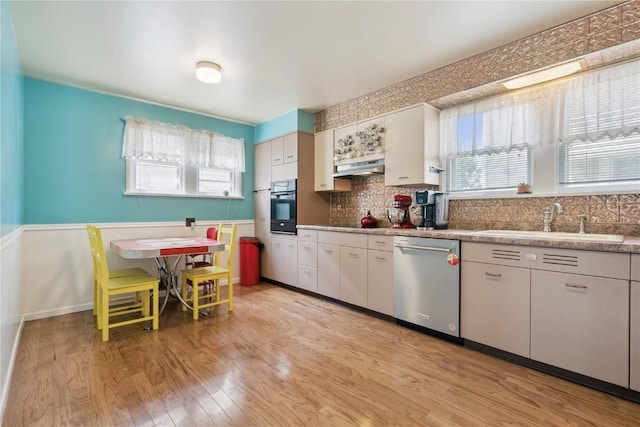 1727 Grande Ave SE, Cedar Rapids, IA 52403 - kitchen featuring dishwasher, oven, tasteful backsplash, light wood finished floors, and a wainscoted wall
