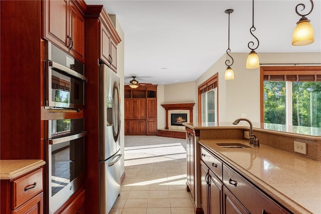 3037 Brookfield Dr, Marion, IA 52302 - kitchen with stainless steel appliances, a warm lit fireplace, a ceiling fan, pendant lighting, and light tile patterned floors