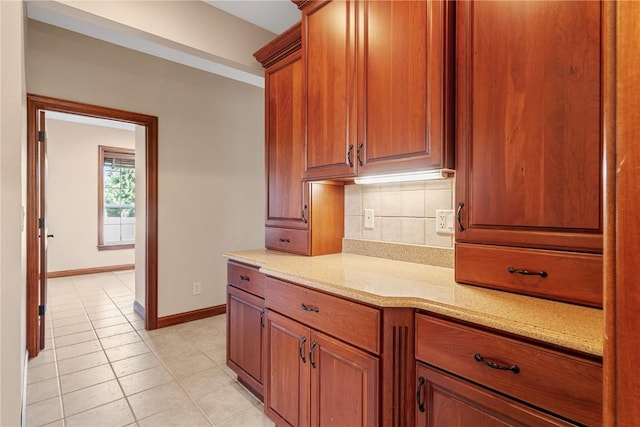 3037 Brookfield Dr, Marion, IA 52302 - kitchen with backsplash, light tile patterned floors, brown cabinets, and light stone counters