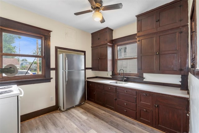 210 16th St SE, Cedar Rapids, IA 52403 - kitchen with freestanding refrigerator, white electric range oven, light wood-style flooring, a ceiling fan, and light countertops