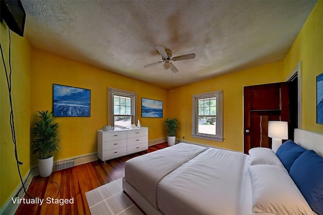 383 21st St SE, Cedar Rapids, IA 52403 - bedroom featuring multiple windows, a baseboard radiator, wood finished floors, and ceiling fan