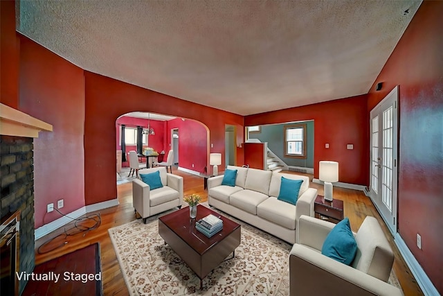 383 21st St SE, Cedar Rapids, IA 52403 - living room with arched walkways, a glass covered fireplace, wood finished floors, and a textured ceiling