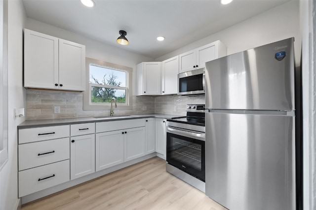 609 34th St NE, Cedar Rapids, IA 52402 - kitchen with appliances with stainless steel finishes, white cabinets, light wood-type flooring, tasteful backsplash, and recessed lighting