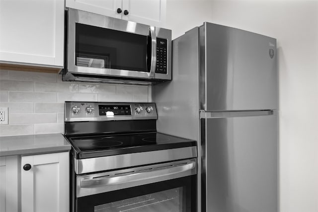 609 34th St NE, Cedar Rapids, IA 52402 - kitchen featuring stainless steel appliances, white cabinets, tasteful backsplash, and dark countertops