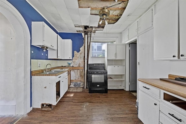 205 E Main St, Lisbon, IA 52253 - kitchen with black range with electric stovetop, dark wood-style floors, white cabinetry, and arched walkways