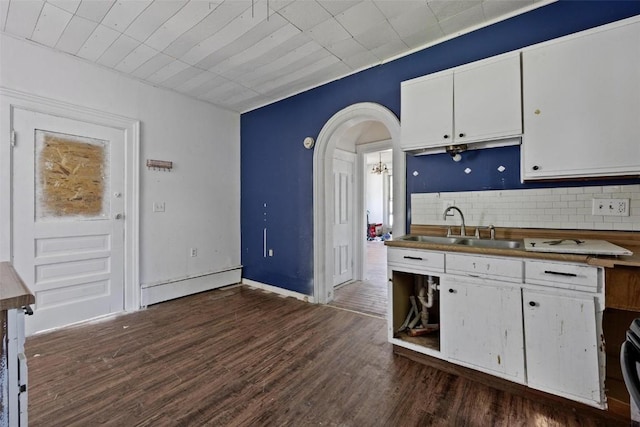 205 E Main St, Lisbon, IA 52253 - kitchen with white cabinetry, tasteful backsplash, dark wood-style floors, and arched walkways