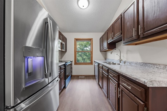 265 Parkview Ct, North Liberty, IA 52317 - kitchen with stainless steel appliances, light countertops, wood finished floors, dark brown cabinetry, and a textured ceiling