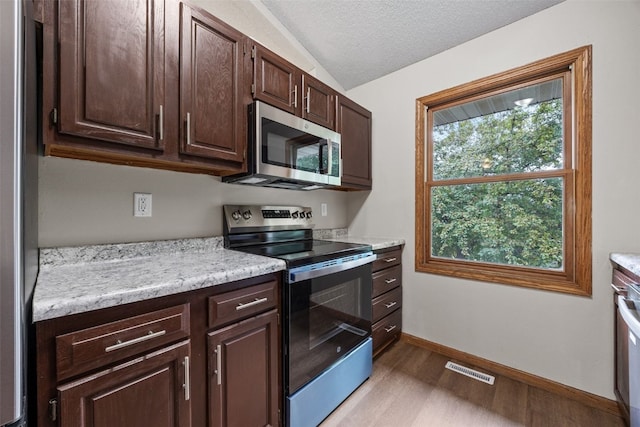 265 Parkview Ct, North Liberty, IA 52317 - kitchen with stainless steel appliances, light wood-style flooring, light countertops, dark brown cabinetry, and lofted ceiling