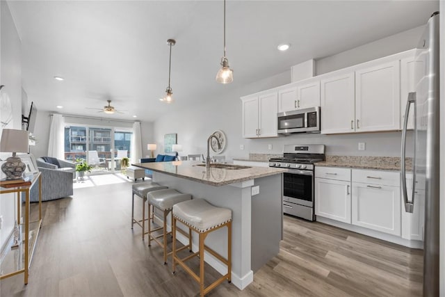 780 Brook Ridge Ave, North Liberty, IA 52317 - kitchen featuring stainless steel appliances, open floor plan, light wood-style floors, ceiling fan, and white cabinetry