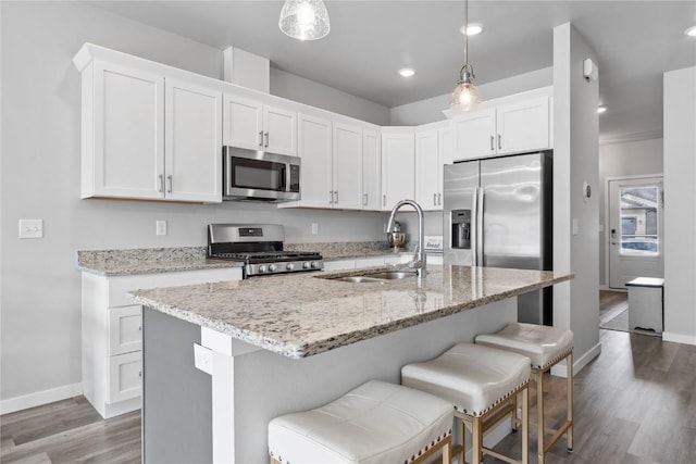 780 Brook Ridge Ave, North Liberty, IA 52317 - kitchen with appliances with stainless steel finishes, wood finished floors, a breakfast bar area, white cabinets, and light stone counters