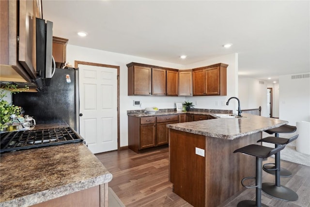 2903 Belle St SW, Cedar Rapids, IA 52404 - kitchen featuring a peninsula, dark wood-style flooring, a kitchen breakfast bar, recessed lighting, and stove