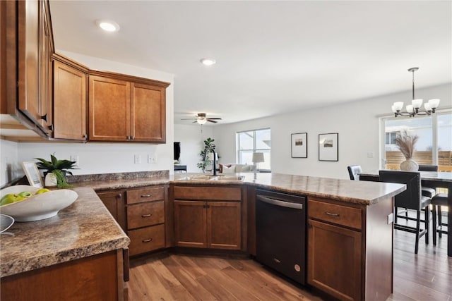 2903 Belle St SW, Cedar Rapids, IA 52404 - kitchen with dishwasher, a peninsula, dark wood-type flooring, a chandelier, and ceiling fan