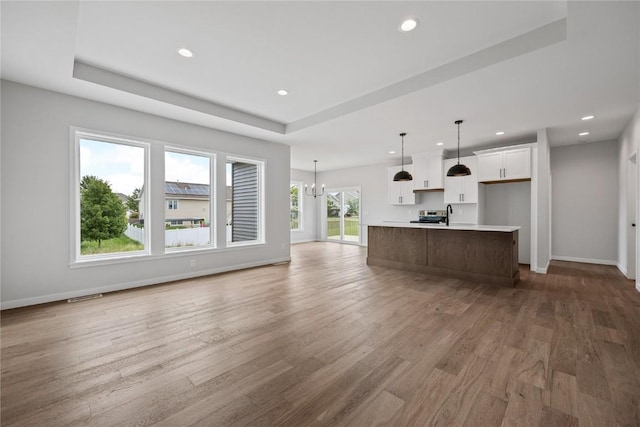 226 Mccarran Ave NE, Cedar Rapids, IA 52402 - unfurnished living room with light wood-style flooring, recessed lighting, a tray ceiling, and a chandelier