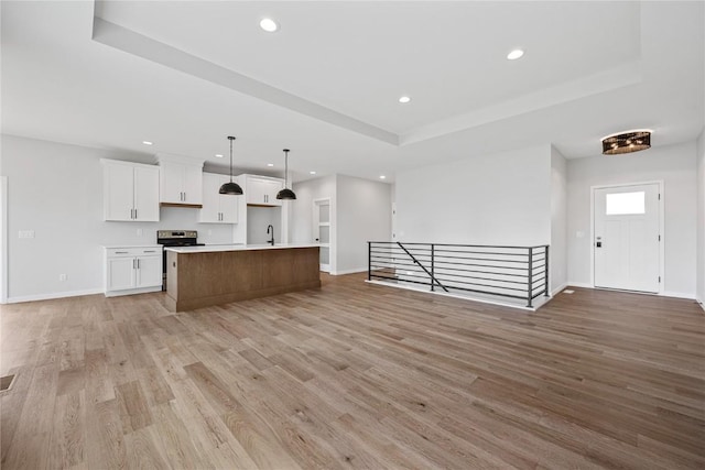 226 Mccarran Ave NE, Cedar Rapids, IA 52402 - kitchen with open floor plan, recessed lighting, white cabinets, a raised ceiling, and light wood-style flooring