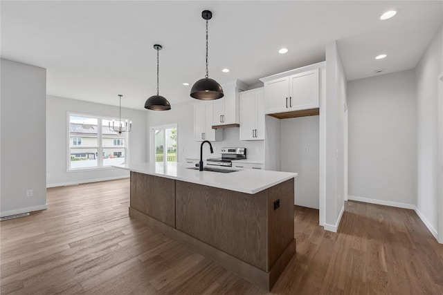226 Mccarran Ave NE, Cedar Rapids, IA 52402 - kitchen with light wood-style floors, white cabinets, light countertops, a kitchen island with sink, and recessed lighting