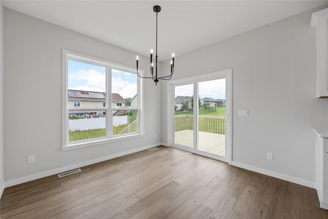 226 Mccarran Ave NE, Cedar Rapids, IA 52402 - unfurnished dining area with a chandelier, wood finished floors, and plenty of natural light