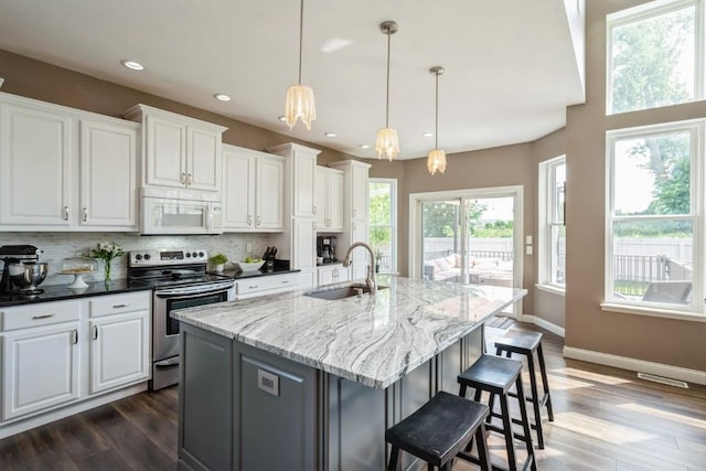 2654 Mulberry Ct, Marion, IA 52302 - kitchen with white microwave, stainless steel range with electric cooktop, dark wood-style flooring, decorative backsplash, and white cabinets
