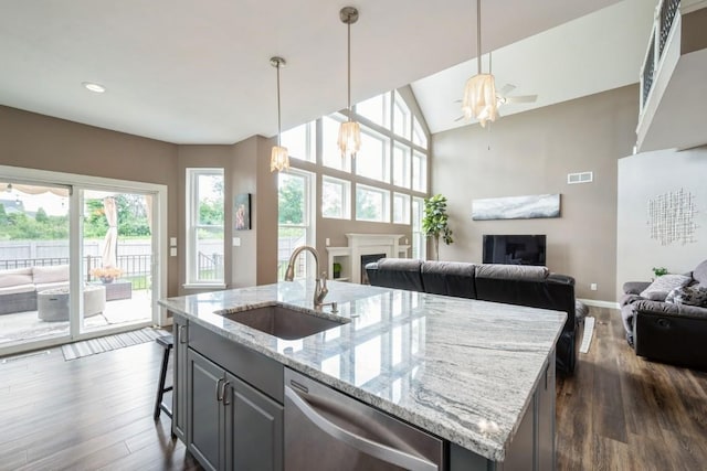 2654 Mulberry Ct, Marion, IA 52302 - kitchen with stainless steel dishwasher, open floor plan, a fireplace, dark wood-type flooring, and a kitchen island with sink