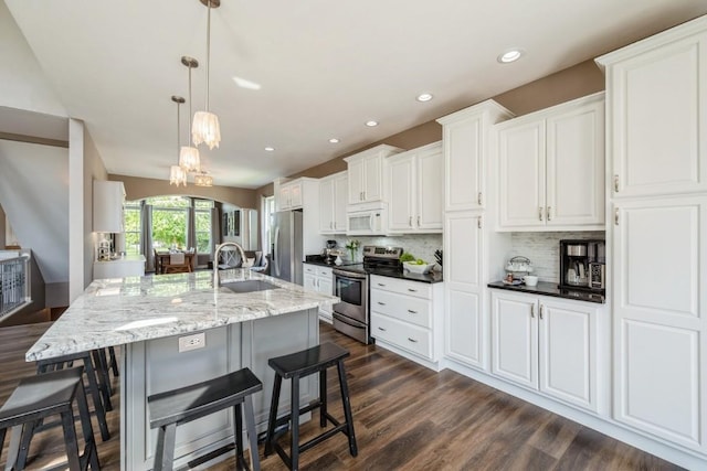 2654 Mulberry Ct, Marion, IA 52302 - kitchen featuring stainless steel appliances, dark wood-style floors, white cabinets, a kitchen bar, and recessed lighting