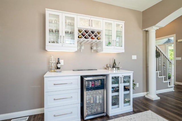2654 Mulberry Ct, Marion, IA 52302 - indoor dry bar featuring wine cooler, dark wood-style flooring, decorative columns, and stairway