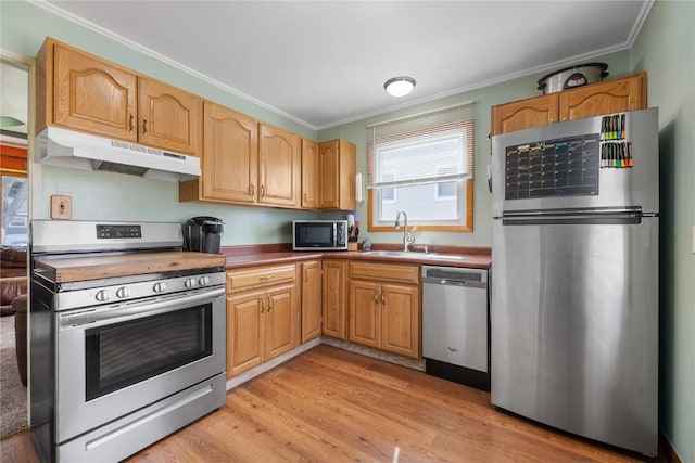 1140 31st St, Cedar Rapids, IA 52402 - kitchen with appliances with stainless steel finishes, under cabinet range hood, ornamental molding, healthy amount of natural light, and light wood finished floors