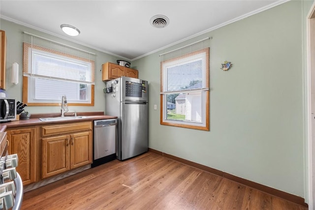 1140 31st St, Cedar Rapids, IA 52402 - kitchen featuring stainless steel appliances, crown molding, light wood-type flooring, and brown cabinetry