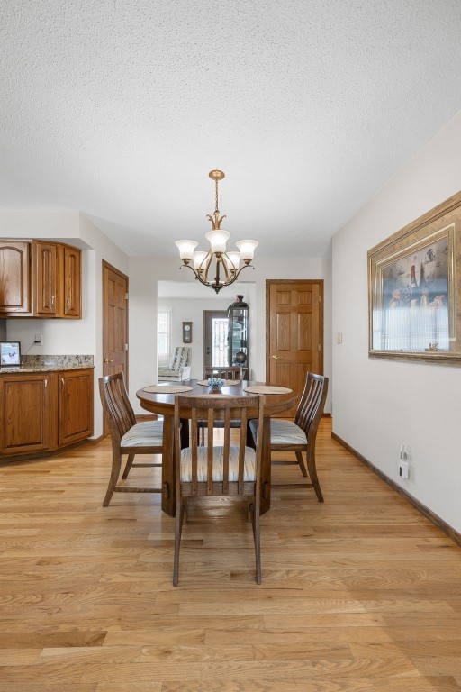 906 29th St NW, Cedar Rapids, IA 52405 - dining room featuring a chandelier, a textured ceiling, and light wood finished floors