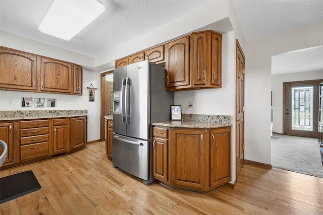 906 29th St NW, Cedar Rapids, IA 52405 - kitchen with stainless steel fridge, brown cabinets, light wood-type flooring, and a textured ceiling
