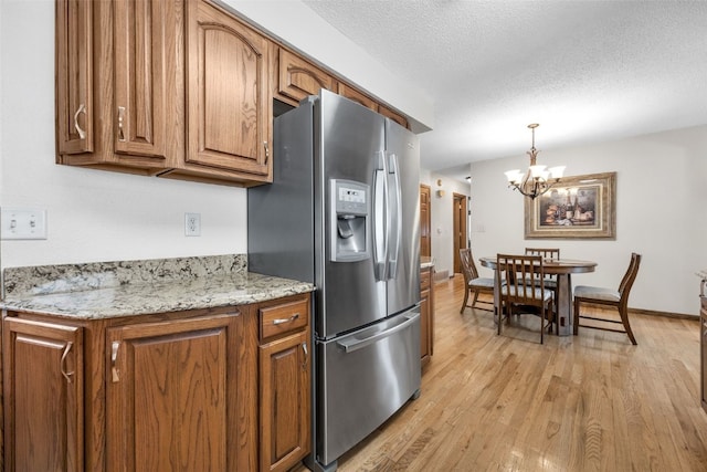 906 29th St NW, Cedar Rapids, IA 52405 - kitchen with stainless steel fridge with ice dispenser, brown cabinets, light wood-style flooring, a chandelier, and a textured ceiling