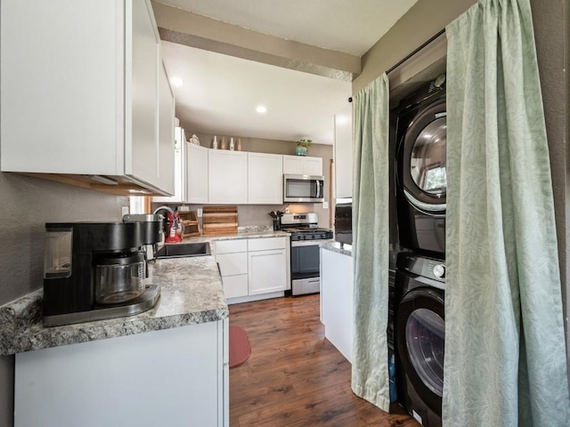 1 E Jefferson Ave S, Urbana, IA 52345 - kitchen featuring stainless steel appliances, stacked washer and clothes dryer, white cabinets, dark wood finished floors, and light countertops