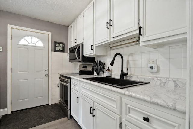 3140 Stratford Ln SW, Cedar Rapids, IA 52404 - kitchen featuring stainless steel appliances, white cabinets, light countertops, wood finished floors, and a textured ceiling
