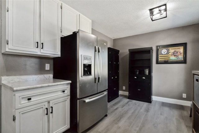 3140 Stratford Ln SW, Cedar Rapids, IA 52404 - kitchen with stainless steel fridge with ice dispenser, light wood-style flooring, white cabinets, a textured ceiling, and light stone counters