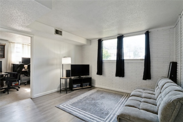 3140 Stratford Ln SW, Cedar Rapids, IA 52404 - living room with a textured ceiling, healthy amount of natural light, a desk, wood finished floors, and brick wall