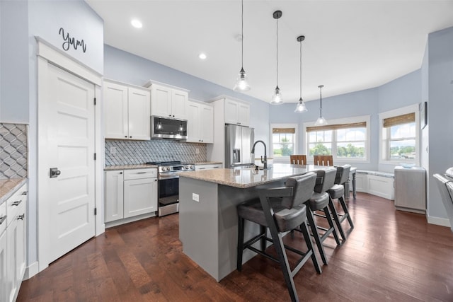605 Alexis Ln, Marion, IA 52302 - kitchen with appliances with stainless steel finishes, backsplash, white cabinetry, a kitchen breakfast bar, and a center island with sink