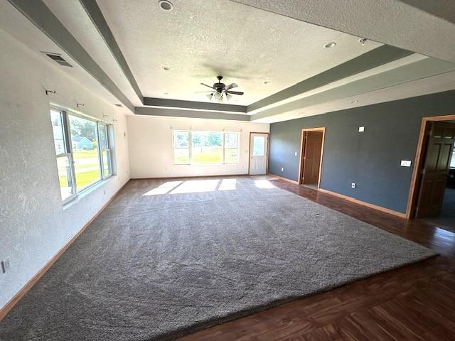 832 E Main St, Central City, IA 52214 - empty room featuring a tray ceiling, a ceiling fan, plenty of natural light, a textured ceiling, and wood finished floors
